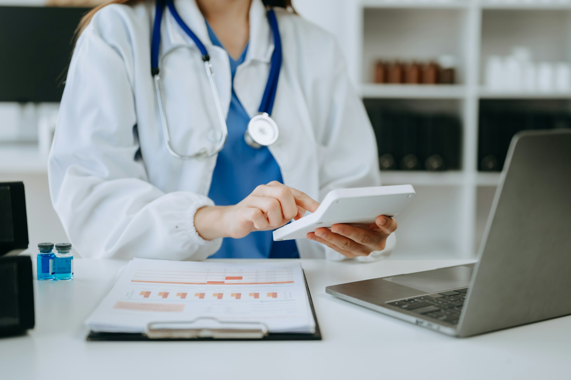 Hand of smart doctor used a calculator and smartphone, tablet for medical costs